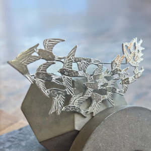 a handmade sterling silver pendant of a flock of starlings in flight, murmuration collection, saw pierced, hand engraved, statement piece, made in glasgow scotland