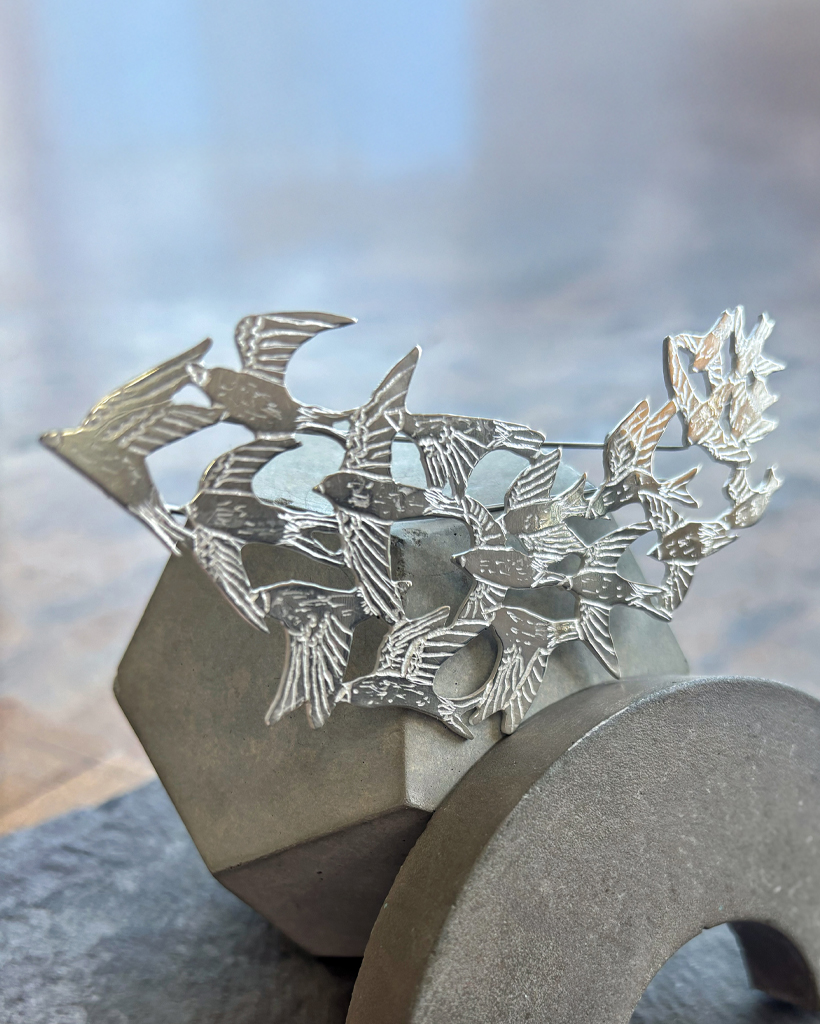 a handmade sterling silver pendant of a flock of starlings in flight, murmuration collection, saw pierced, hand engraved, statement piece, made in glasgow scotland