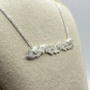 Artisan handmade sterling silver bar necklace featuring a flock of flying starlings, crafted by Stacy Bias Jewellery in Glasgow, Scotland and displayed on a beige bust.