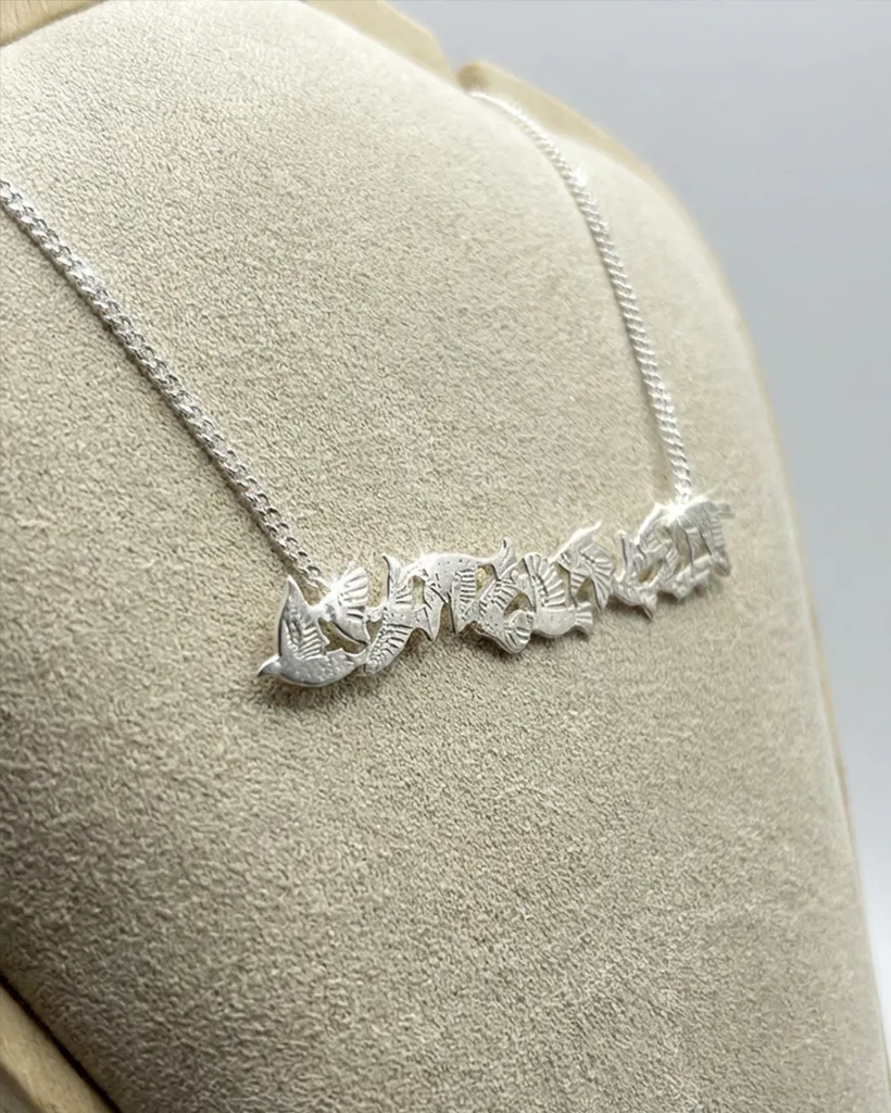 Artisan handmade sterling silver bar necklace featuring a flock of flying starlings, crafted by Stacy Bias Jewellery in Glasgow, Scotland and displayed on a beige bust.