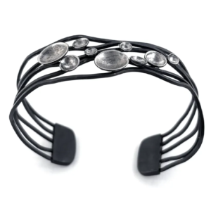 Open oxidised sterling silver cuff bracelet at an angle, wavy dark bands and flat terminals with a cluster of domes