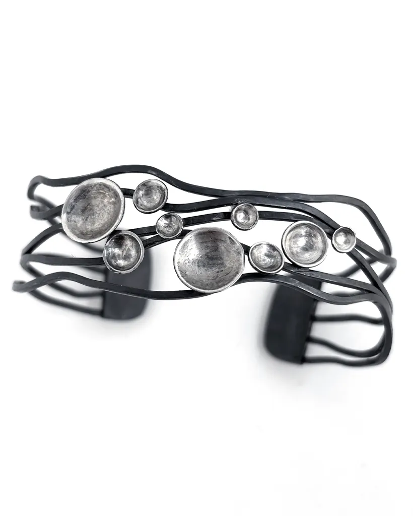 Sterling Silver Murmuration Dot Cuff, Oxidised Bands with Polished Domes Oxidised sterling silver cuff bracelet from above, dark wavy bands set with bright polished domed discs, on white