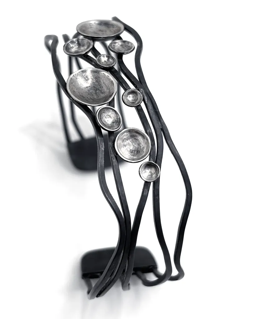Oxidised sterling silver cuff stood upright, wavy dark bands flowing like currents set with cupped silver domes
