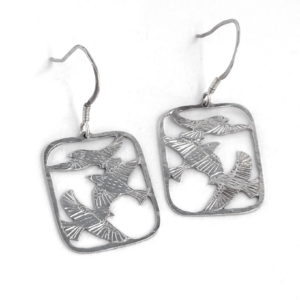 Pair of sterling silver three bird drop earrings laid flat, saw-pierced starlings in flight and hammered hooks