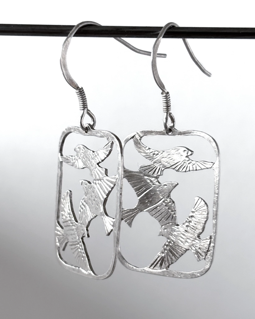 Close view of sterling silver three bird drop earrings, saw-pierced starlings in flight within open frames