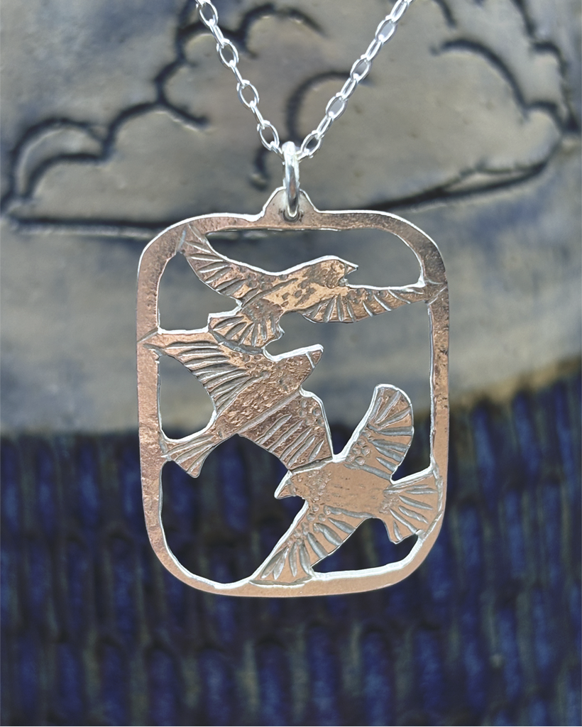 Handmade Sterling Silver Murmuration Necklace | Scottish Artisan Bird Pendant Artisan handmade sterling silver pendant featuring three hand-engraved flying birds in a cutout frame, crafted by Stacy Bias Jewellery in Glasgow, Scotland.