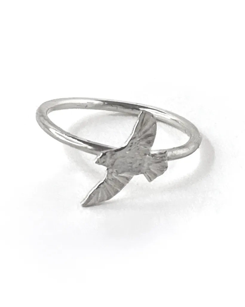 Single sterling silver bird ring on a slim band, an engraved bird in flight with downswept wings, on white