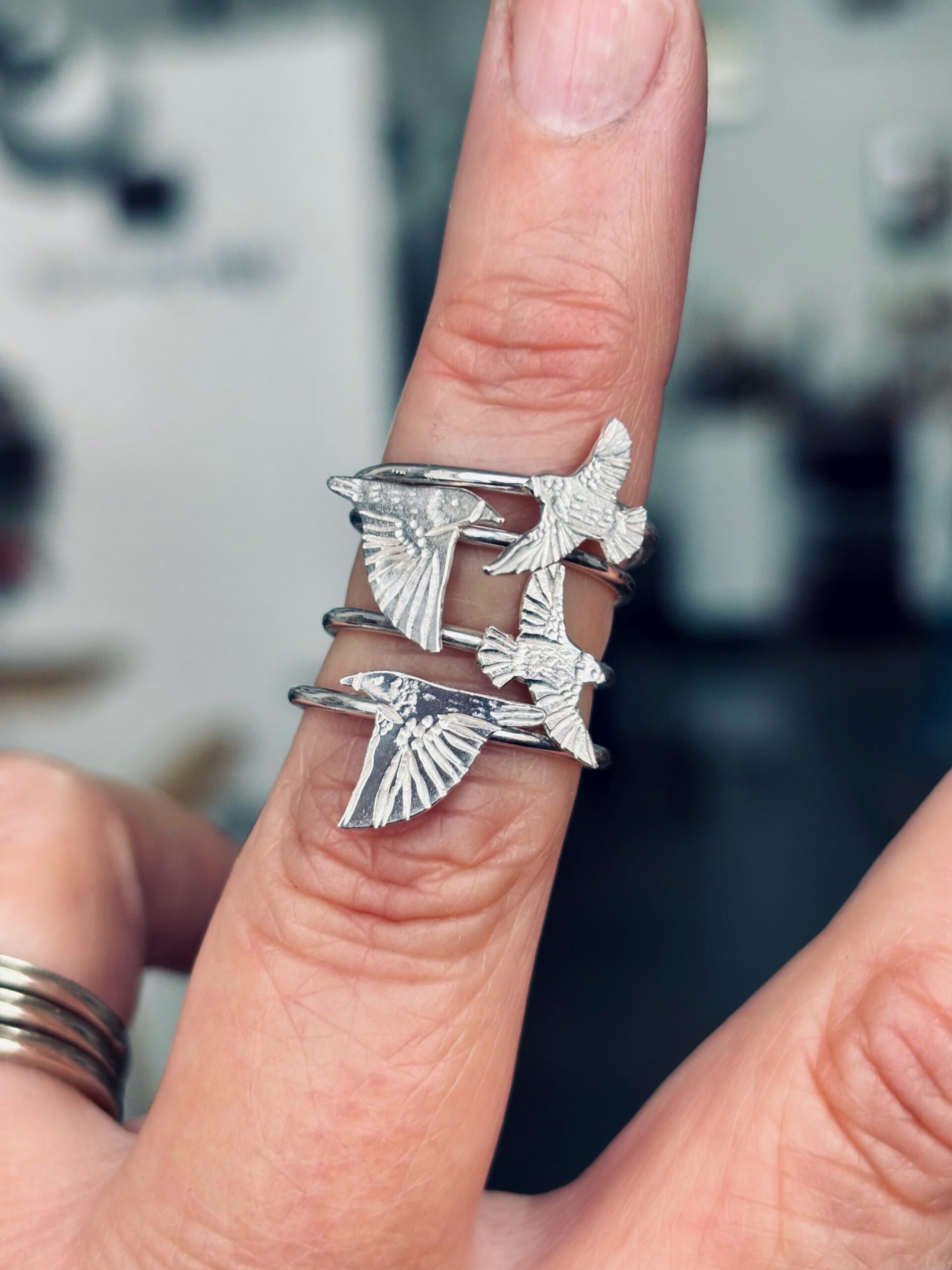 Silver Bird Stacking Rings Worn as a Flock, Handmade Sterling Silver Several sterling silver bird rings stacked on a finger, each an engraved bird in flight with spread wings, worn as a flock