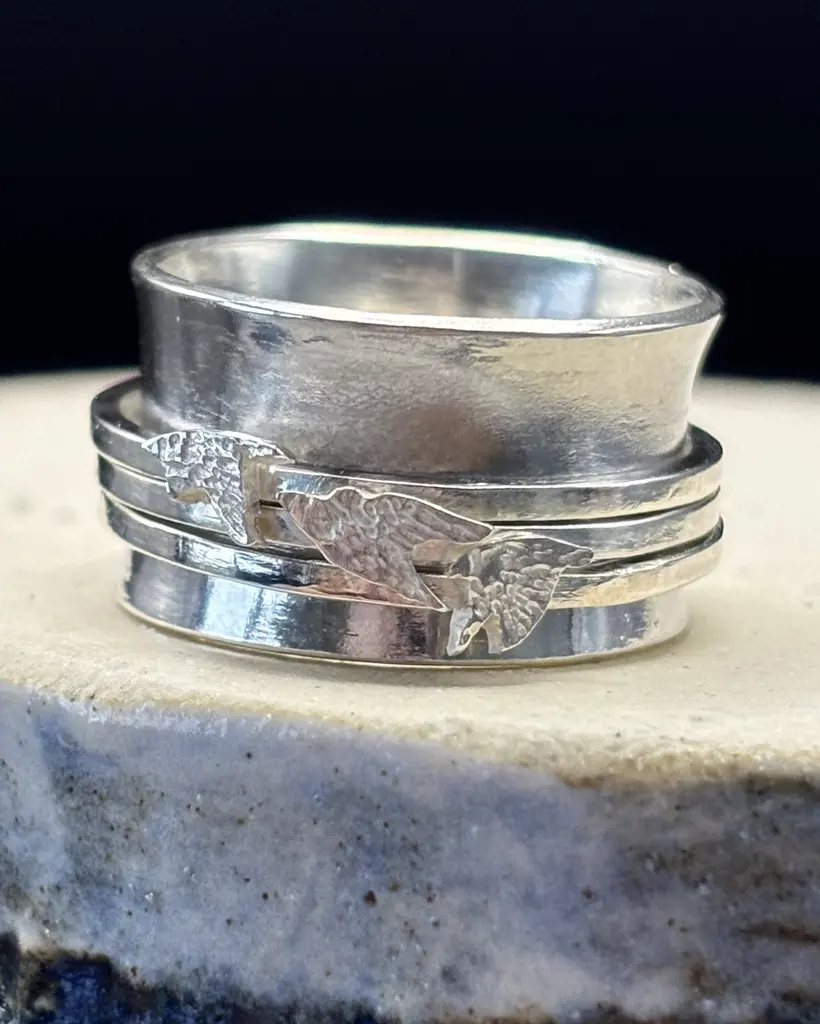 Handmade sterling silver spinner ring, wide band with three slim spinning bands each holding an engraved starling