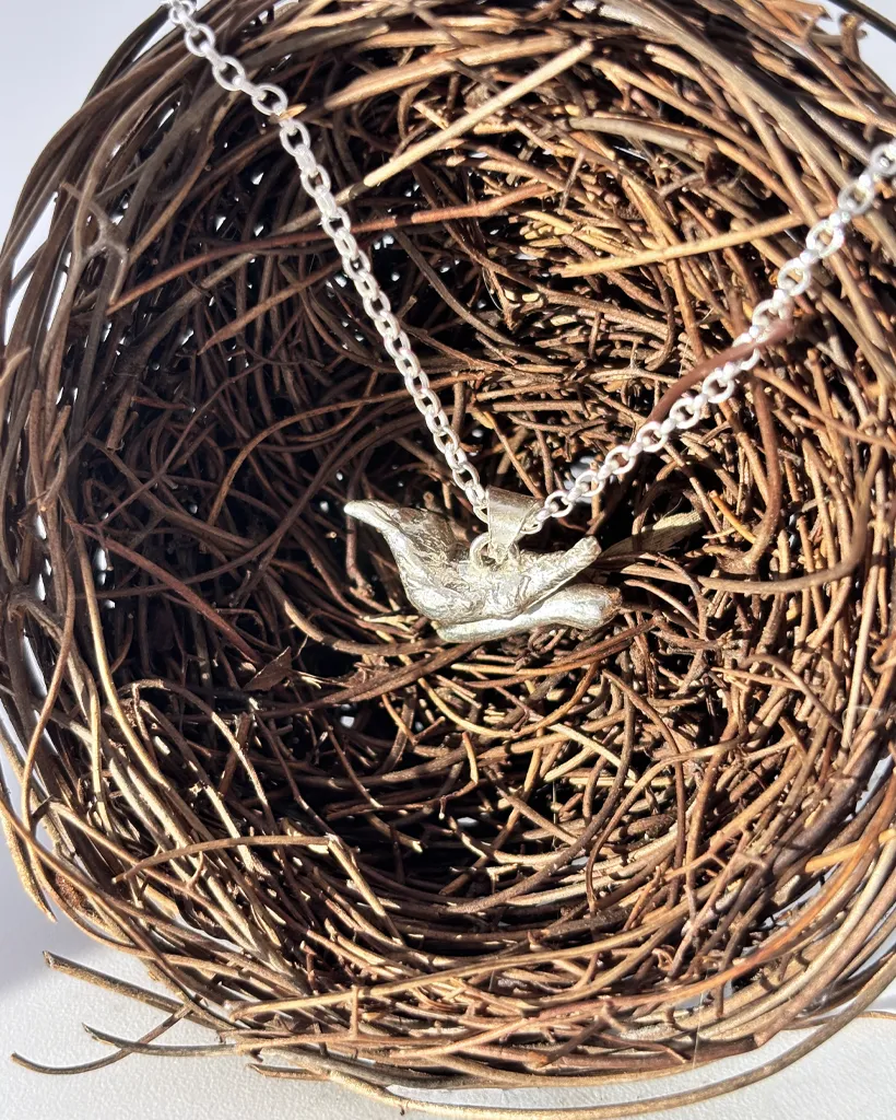 a water cast 925 sterling silver pendant in the shape of a bird and branch