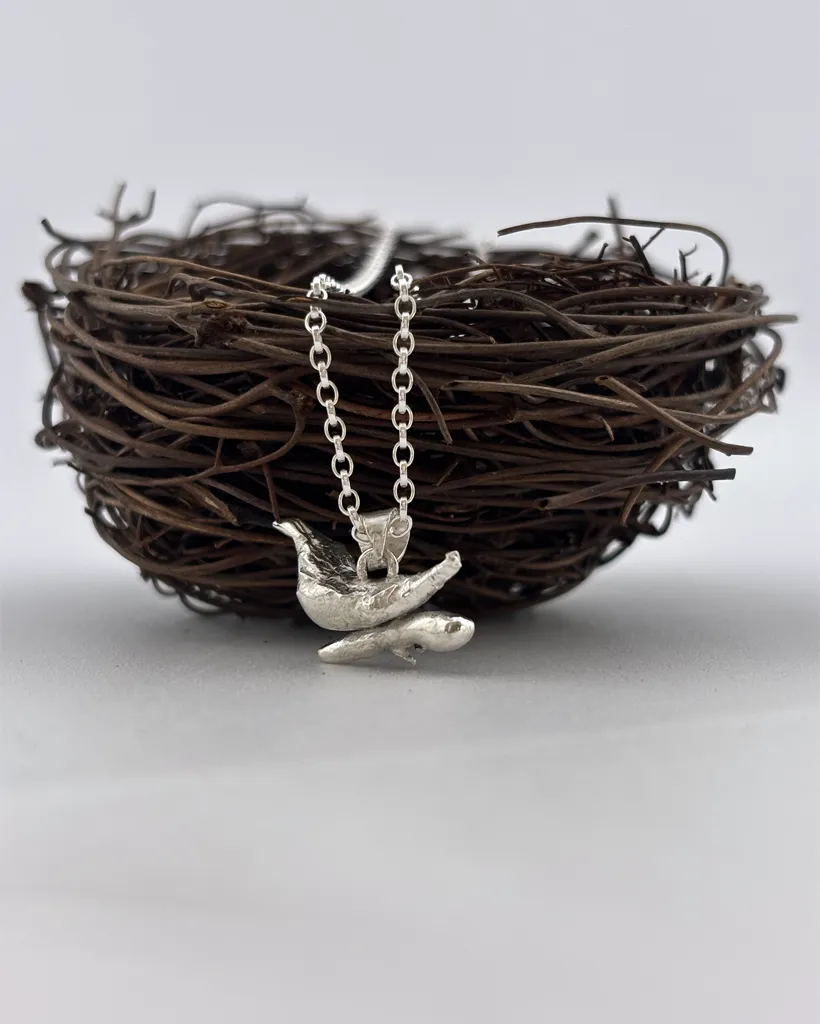 a water cast 925 sterling silver pendant in the shape of a bird and branch