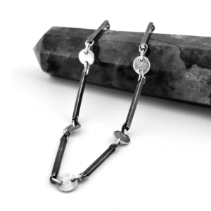 Artisan handmade sterling silver bar and disc link bracelet designed by Stacy Bias Jewellery in Glasgow UK draped over a dark grey crystal point.