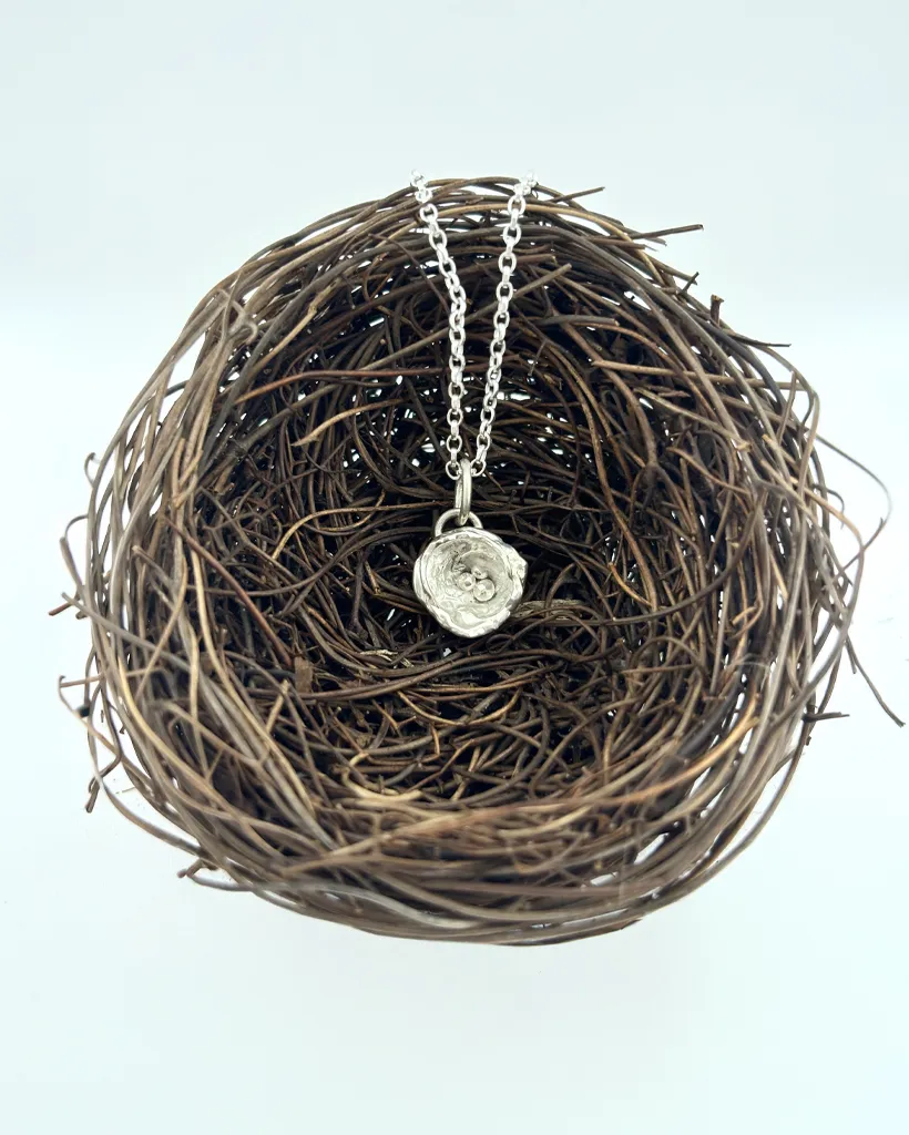 a water cast 925 sterling silver pendant in the shape of a birds nest with eggs