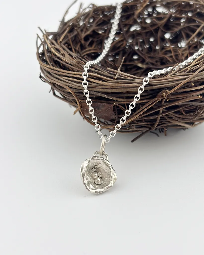 a water cast 925 sterling silver pendant in the shape of a birds nest with eggs