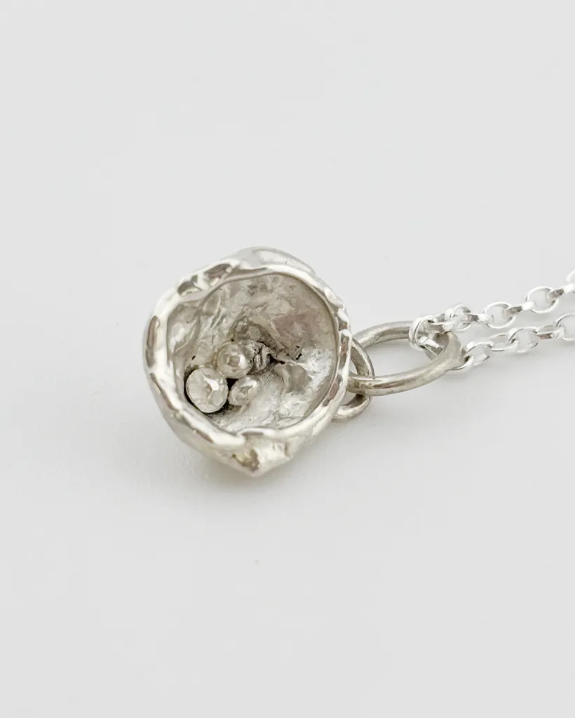 a water cast 925 sterling silver pendant in the shape of a birds nest with eggs