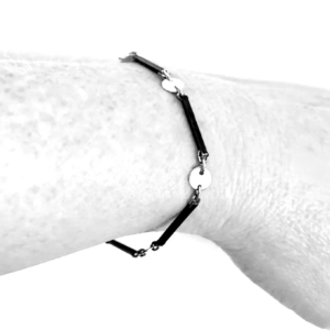 Sterling silver dot and dash chain bracelet draped on a wrist, oxidised bar links joined to bright silver circles
