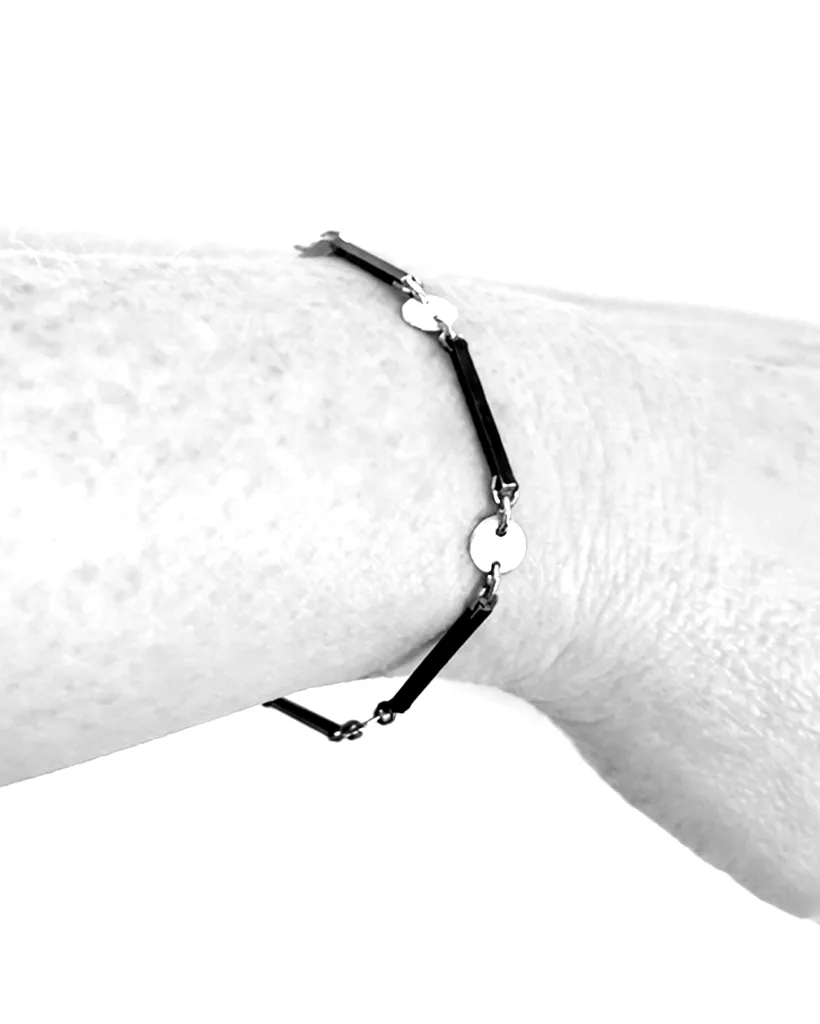 Sterling silver dot and dash chain bracelet draped on a wrist, oxidised bar links joined to bright silver circles
