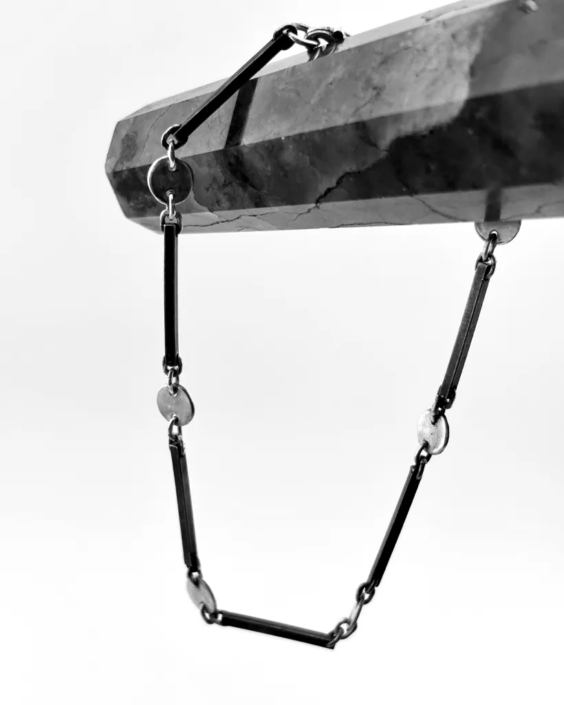 Oxidised sterling silver dot and dash chain draped over a dark crystal point, bar links joined to silver circles