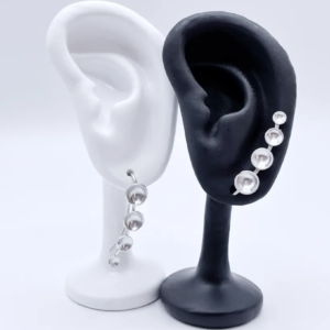 sterling silver ear climber earrings with four cascading dots from small to large. One is positioned to climb up the ear, one is rotated to dangle downwards.