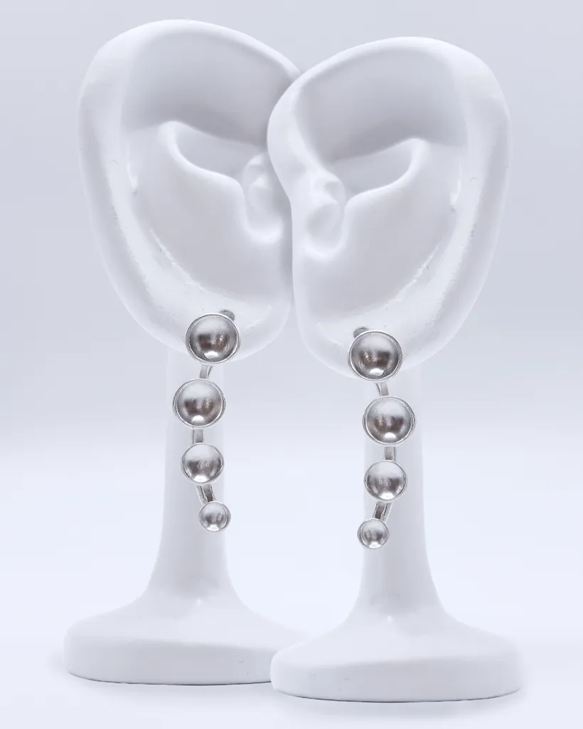 a pair of sterling silver ear climber earrings with four cascading domed silver dots from small to large. Rotated, in this case, to dangle nicely downward from the ear