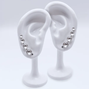 a pair of sterling silver ear climber earrings with four cascading domed silver dots from small to large.