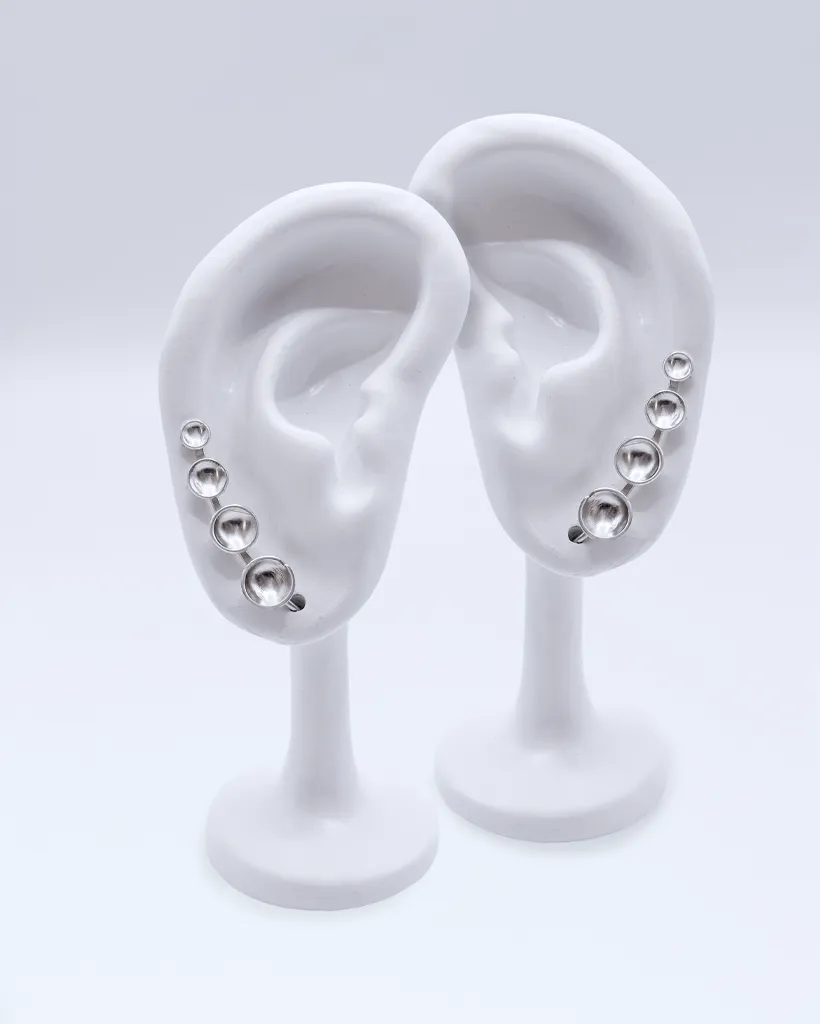 a pair of sterling silver ear climber earrings with four cascading domed silver dots from small to large.