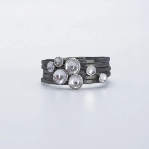 a stack of sterling silver rings with oxidised bands and silver domed dots which, collectively, form a symbolic flock of birds in flight