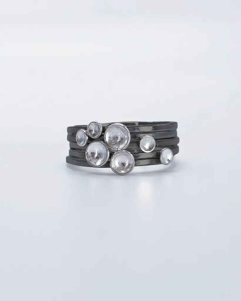 a stack of sterling silver rings with oxidised bands and silver domed dots which, collectively, form a symbolic flock of birds in flight