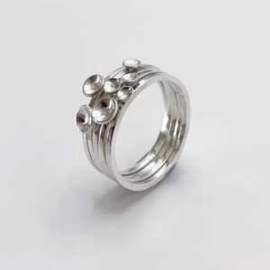 Polished sterling silver Murmuration Dot stacking rings at a high angle, five separate bands with domed dots on top