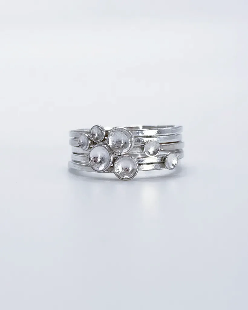 Polished sterling silver Murmuration Dot rings stacked head-on, domed dots clustered into a flock of birds in flight