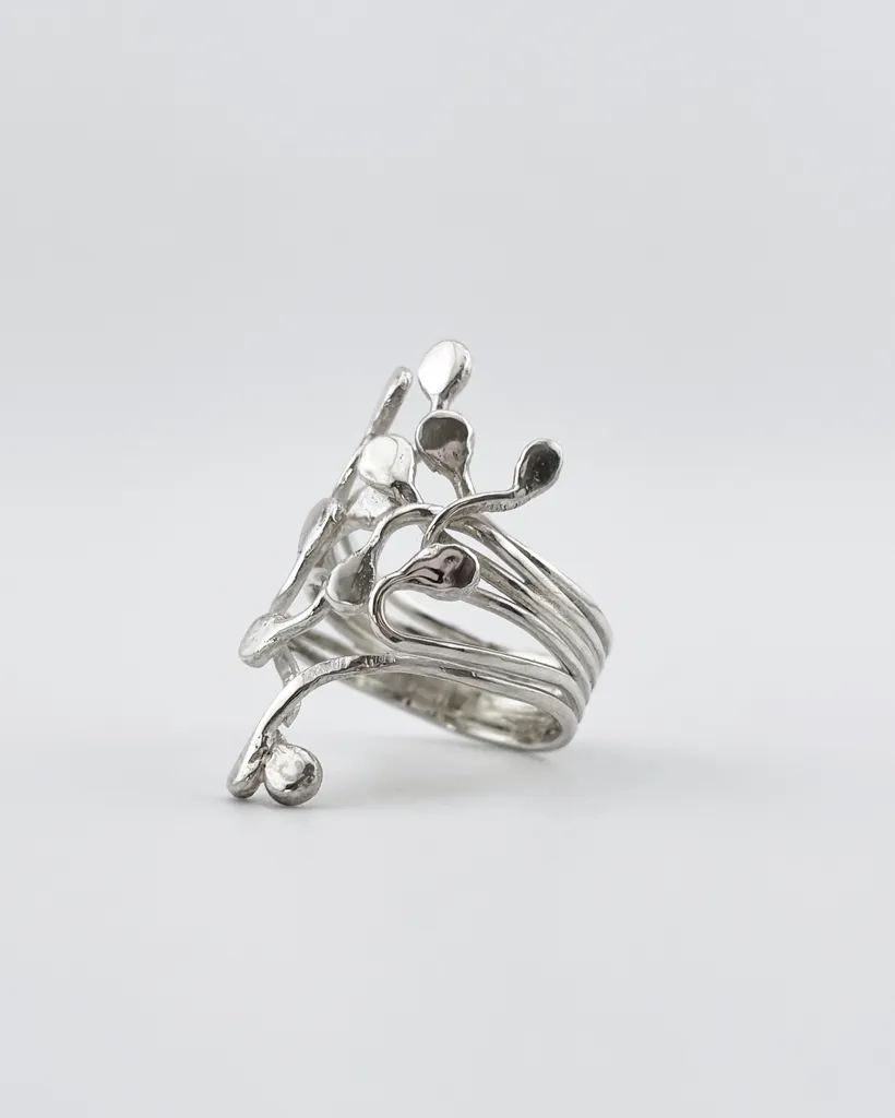 Three-quarter studio view of the handmade sterling silver Squiggle ring showing the layered split band and organic climbing tendrils on a white background.