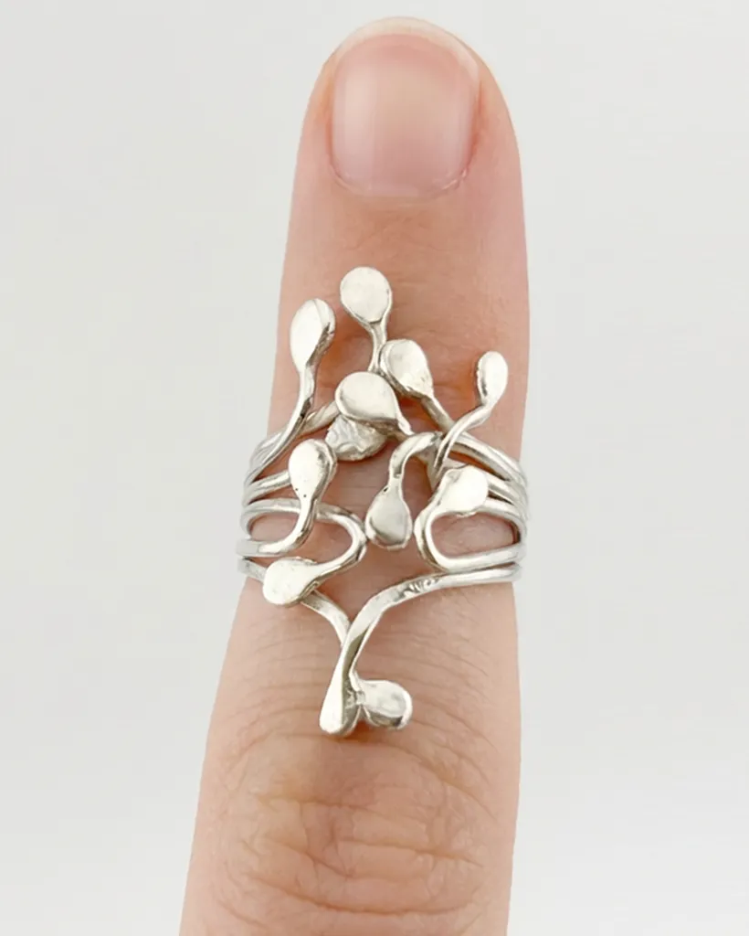 Top down view of the handmade sterling silver Squiggle ring worn on a finger, showcasing the organic climbing droplets against a clean light background.