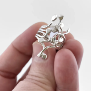 Silver Squiggle statement ring held in a hand to show scale. Sculptural artisan jewelry by Stacy Bias.