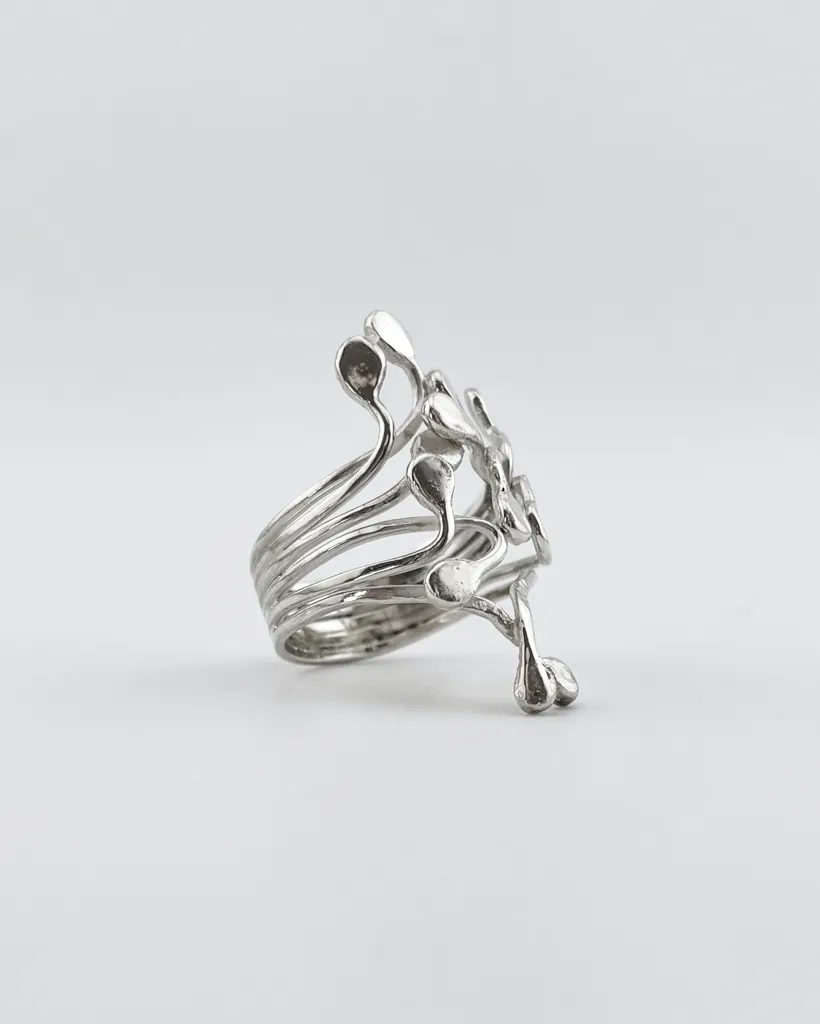 Profile studio shot of the handmade sterling silver Squiggle ring showing the multi-strand split band construction and fluid metal droplets on a white background.