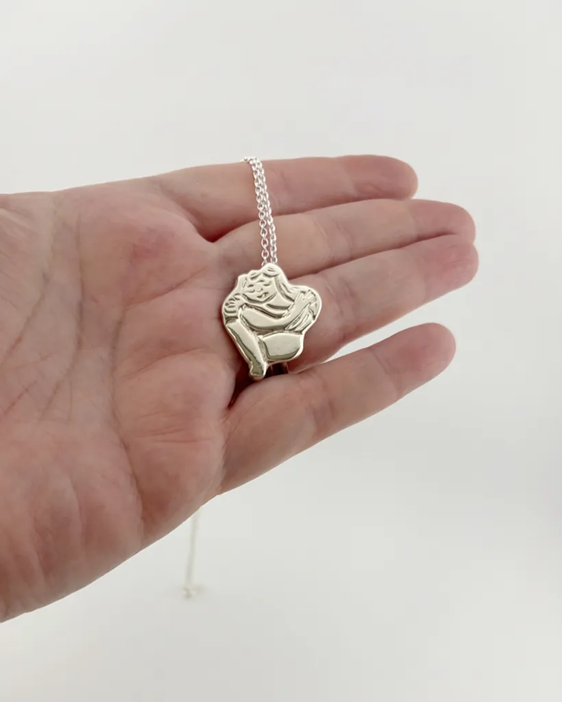 Chunky silver Self Love pendant necklace held in an open hand to show scale. Handcrafted by Stacy Bias.