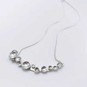 Bright sterling silver Murmuration Dot Arc necklace with polished domed circles. Handcrafted by Stacy Bias.