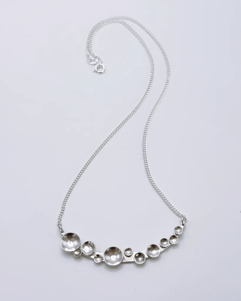 Bright silver Murmuration Dot Arc pendant necklace on fine curb chain with clasp. Handcrafted by Stacy Bias.