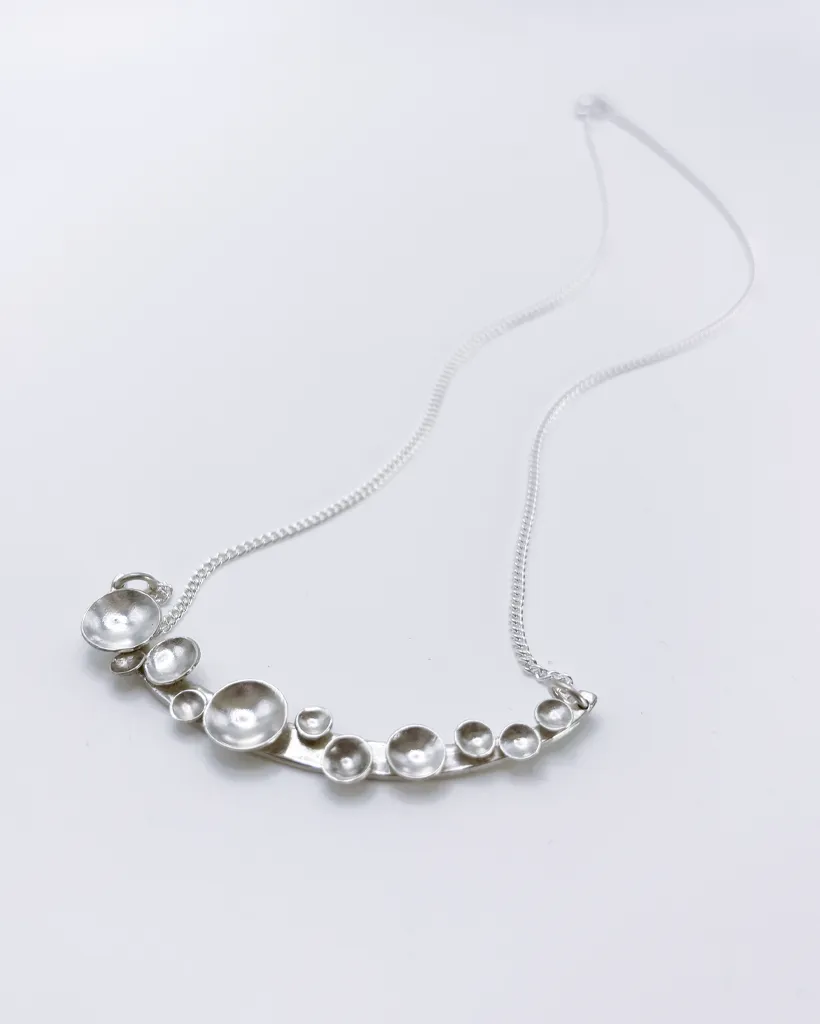 Bright sterling silver Murmuration Dot Arc necklace with polished domed circles. Handcrafted by Stacy Bias.