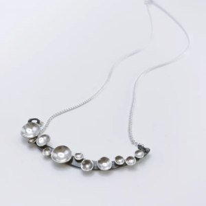 Oxidised silver Murmuration Dot Arc pendant with polished domed dots on a fine chain. Handmade by Stacy Bias.