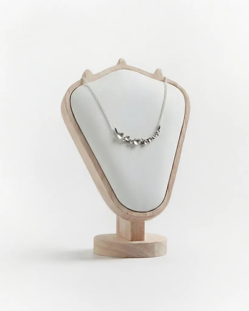 Oxidised silver Murmuration Dot Arc necklace displayed on a wooden and cream neck bust. Handcrafted by Stacy Bias.