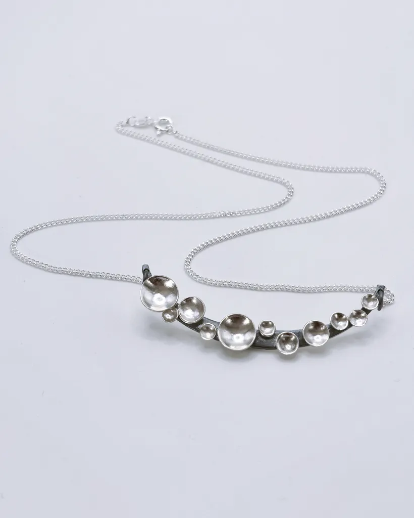 Oxidised Silver Murmuration Dot Arc Necklace | Stacy Bias Oxidised silver Murmuration Dot Arc necklace with chain and clasp laid flat. Handcrafted by Stacy Bias.