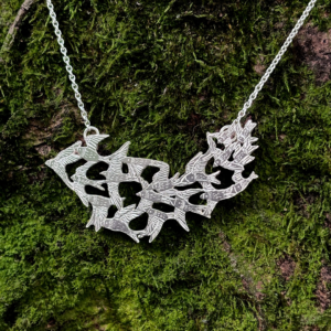925 sterling silver statement necklace depicting a starling bird flock in flight, resting on rich forest floor foliage.