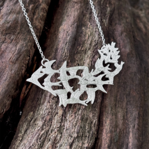 Fully detailed view of the handmade silver Murmuration necklace by Stacy Bias Jewellery over dark natural wood.